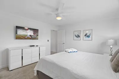a white bedroom with a bed and a tv on the wall at Disney Getaway Private Pool Themed Bedrooms. Book Now SLR370 in Kissimmee