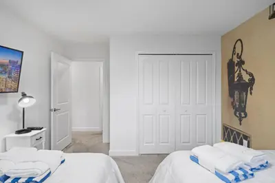a white bedroom with two beds and a door at Disney Getaway Private Pool Themed Bedrooms. Book Now SLR370 in Kissimmee