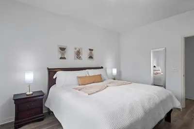 a white bedroom with a large bed and a nightstand at Disney Getaway Private Pool Themed Bedrooms. Book Now WLV5 in Kissimmee