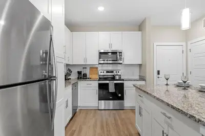 a kitchen with white cabinets and a stainless steel refrigerator at Pinnacle Apartments W Amenties by Heavenly Homes in Orlando