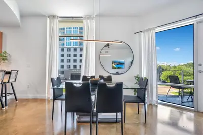 a dining room with a table and chairs and a mirror at 3 bedroom Corner Suite in Orlando