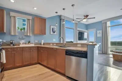 a kitchen with wooden cabinets and blue walls at 2 Bdrm Penthouse with Billiards in Orlando