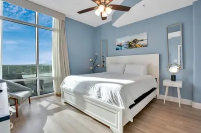 a bedroom with a white bed and a ceiling fan at 2 Bdrm Penthouse with Billiards in Orlando