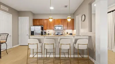 a kitchen with a bar with white stools at Near Universal's Epic Universe Suite -3BR in Orlando