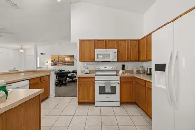 a kitchen with wooden cabinets and a white stove top oven at Single Story Villa with Pool Views and Family Fun in Orlando