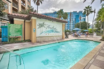 a swimming pool at a resort with a building and palm trees at Poolside Oasis 7 Mi to Disney and Universal in Orlando