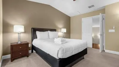 a bedroom with a large white bed with a nightstand and a door at Sunny Summer Magic - Stay in TownHome by Disney in Orlando