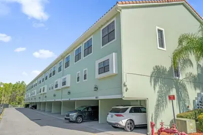 a building with two cars parked in a parking lot at Sunny Summer Magic - Stay in TownHome by Disney in Orlando