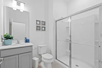 a white bathroom with a shower and a toilet at Casa Luxo 5 Suítes | Perto da Epic Universe in Orlando