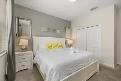 a bedroom with a large white bed with yellow pillows at Luxe Lakeview Private Pool SPA 10 Min Disney in Kissimmee