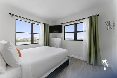 a white bedroom with a bed and two windows at Lake View Top Floor 2 Bed 2 Bath Condo with Balcony in Orlando