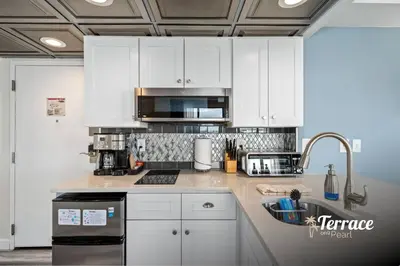 a kitchen with white cabinets and a sink at Skyline Studio Condo with Private Terrace and Epic Universe View in Orlando