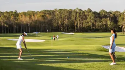 two women playing golf on a golf course at Castle Keys Salt Water Pool Home 10 mins to Disney in Kissimmee
