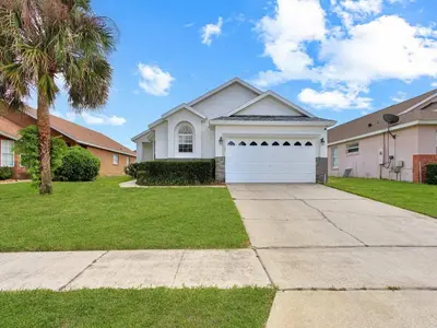 a house with a white garage and a palm tree at Castle Keys Salt Water Pool Home 10 mins to Disney in Kissimmee
