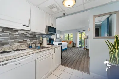 a kitchen with white cabinets and a living room at Delightful Studio Condo with Garden View Balcony 7 Mins to Universal in Orlando