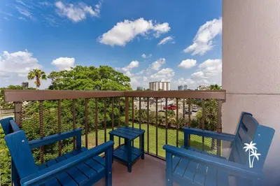 two blue chairs on a balcony with a view at Delightful Studio Condo with Garden View Balcony 7 Mins to Universal in Orlando