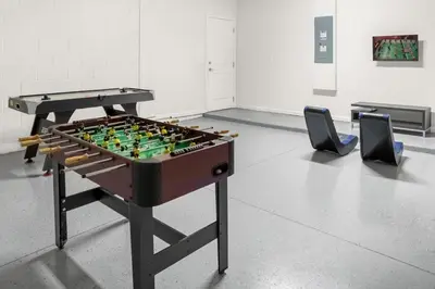 a foosball table in a room with two chairs at Upstay - Resort Home w Cinema Pool & Lake View in Kissimmee