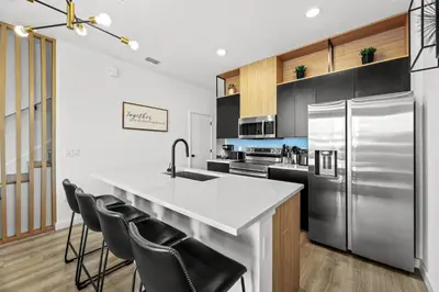 a kitchen with a stainless steel refrigerator and black cabinets at Modern Townhome 10min to Disney in Kissimmee