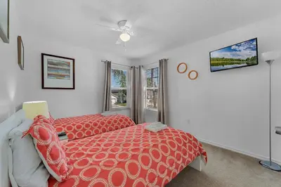 a bedroom with a red bed and a window at Casa Vista Lago c/ Piscina Privada – Próx. Disney in Kissimmee