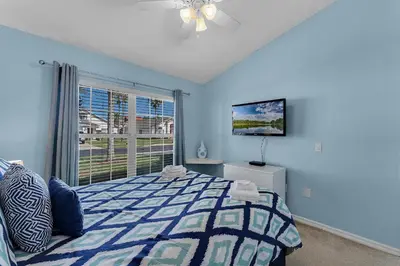 a blue bedroom with a bed and a window at Casa Vista Lago c/ Piscina Privada – Próx. Disney in Kissimmee