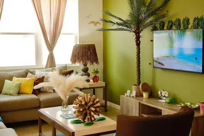 a living room with a couch and a palm tree at Margaritaville House Close to Universal in Kissimmee