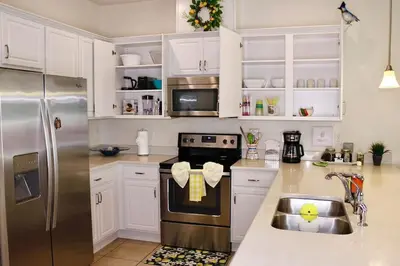 a kitchen with white cabinets and a stainless steel refrigerator at Margaritaville House Close to Universal in Kissimmee
