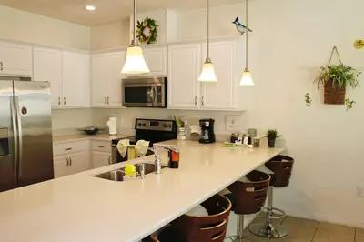a kitchen with white cabinets and a stainless steel refrigerator at Margaritaville House Close to Universal in Kissimmee