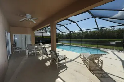 a patio with chairs and a swimming pool with windows at Tranquil Waters Haven by Paradise Resort Vacations in Kissimmee