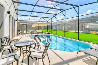 a patio with a table and chairs and a swimming pool at UPSTAY- 10BR Mansion wPrivate Pool and Games Room in Kissimmee