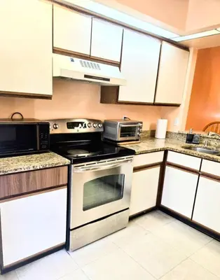 a kitchen with stainless steel appliances and white cabinets at Retro 3 Bedroom Economy Family Home with washer and dryer in unit in Kissimmee