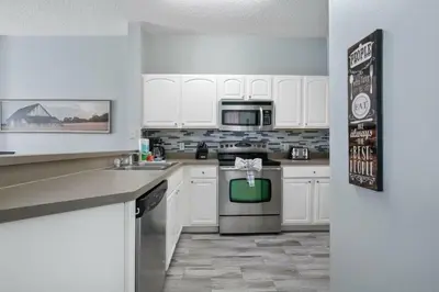 a kitchen with white cabinets and a stove top oven at Casa 3 Quartos no Lake Berkley Resort in Kissimmee