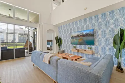 a living room with a blue couch and a table at Tiki Palms Play and Pool Near Disney in Kissimmee