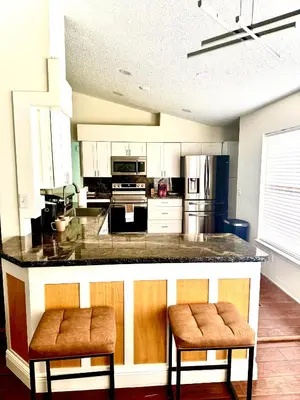 a kitchen with a large counter with two stools at Tropical Paradise in Orlando