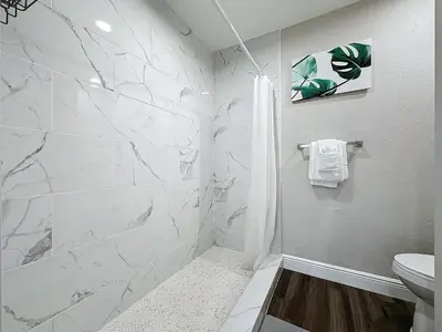 a white bathroom with a shower and a toilet at Parkway Palms Resort 1 bed condo mins to Disney. in Orlando