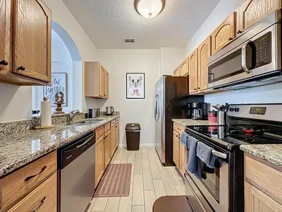 a kitchen with wooden cabinets and a stove top oven at Magical 3BR/2BA Disney-Themed Condo in Orlando