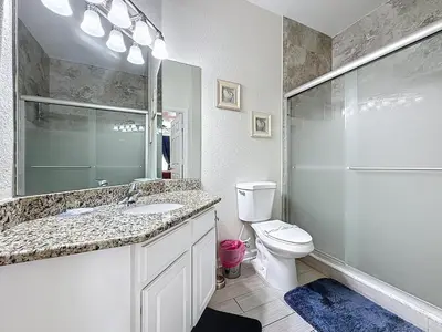 a bathroom with a sink and a toilet and a mirror at Magical 3BR/2BA Disney-Themed Condo in Orlando