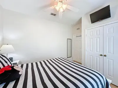 a bedroom with a striped bed with a ceiling fan at Magical 3BR/2BA Disney-Themed Condo in Orlando