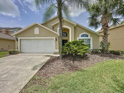 a house with a garage and a palm tree at Terra Verde Resort 4 Bed Pool/Spa Villa in Kissimmee