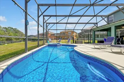 a swimming pool with two chairs and a house at Emerald Island Resort 6 Bed Pool & Spa in Kissimmee