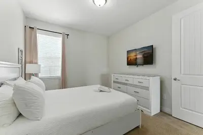 a white bedroom with a bed and a window at 7416 Encore Reunion poolspa 11 guests 5 bdrs BBQ in Orlando