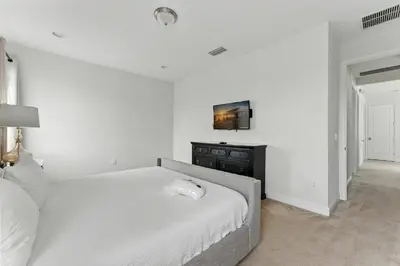 a white bedroom with a bed and a dresser at 7416 Encore Reunion poolspa 11 guests 5 bdrs BBQ in Orlando