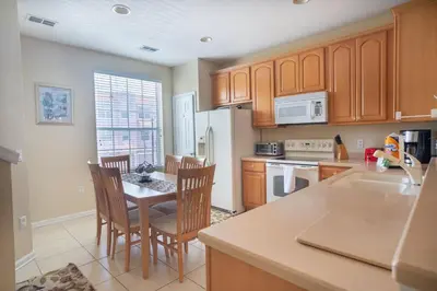 a kitchen with wooden cabinets and a table with chairs at Vista Cay Townhome Near Universal & Disney in Orlando