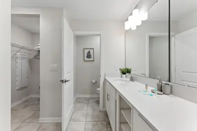 a white bathroom with a sink and a mirror at Elegant 2BR in Storey Lake Top Location in Kissimmee