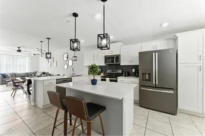 a kitchen with a refrigerator and a table and chairs at Elegant 2BR in Storey Lake Top Location in Kissimmee