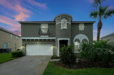a house with a garage and a palm tree at Ever After Estate in Kissimmee