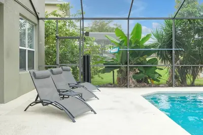 a group of chairs sitting next to a swimming pool at Ever After Estate in Kissimmee