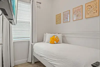 a white bedroom with a bed with a stuffed animal on it at The Flamingo Nest - Kid Friendly in Orlando
