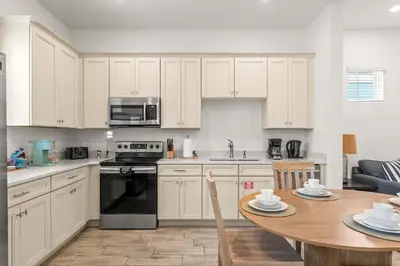 a kitchen with white cabinets and a wooden table at The Flamingo Nest - Kid Friendly in Orlando