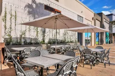 a group of tables and chairs with an umbrella at The Flamingo Nest - Kid Friendly in Orlando