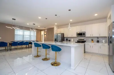 a kitchen with white cabinets and blue bar stools at Stunning Mansion 15 ensuites in Kissimmee
